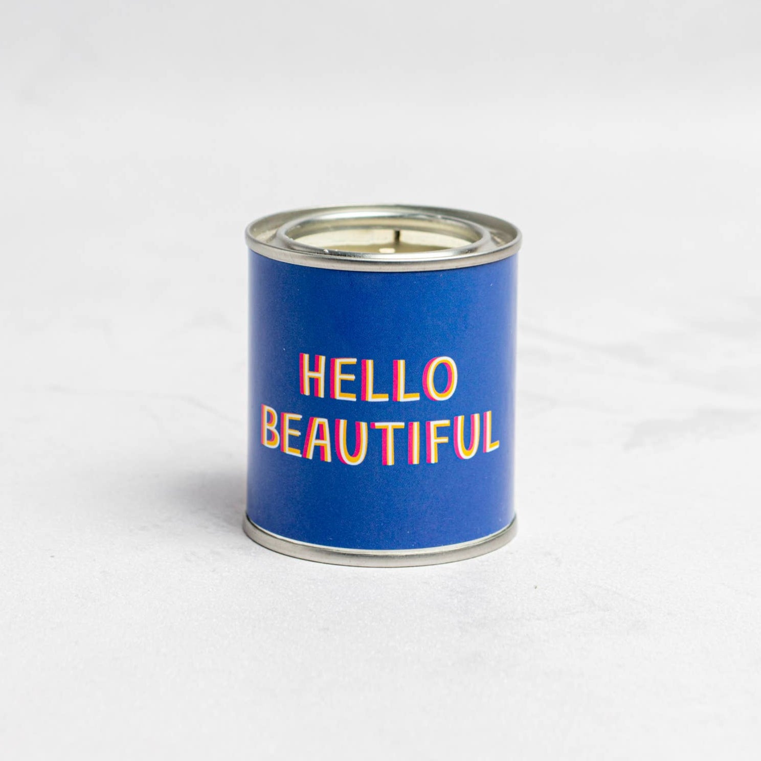 A blue cylindrical candle with the text 'HELLO BEAUTIFUL' printed in white.