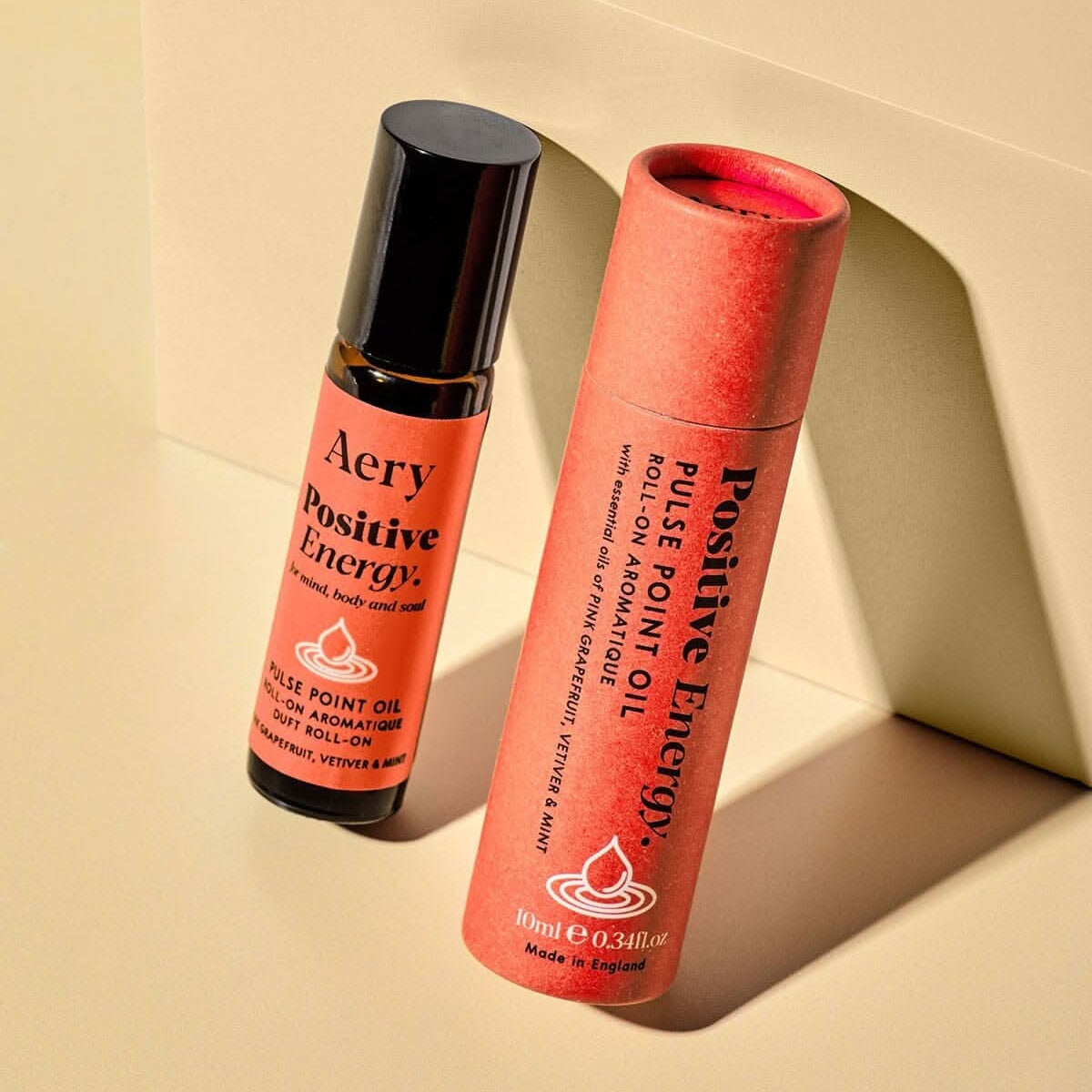 Two Aery Positive Energy roller bottles on a beige background