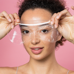 Woman holding a clear face shield against a pink background
