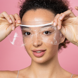 Woman holding a clear face shield against a pink background