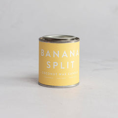 A can of Banana Split coconut wax candle with a yellow label on a neutral background.