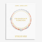 A Joma Jewellery 'Friendship Forever' bracelet displayed on its white presentation card. The bracelet features peach-pink beads, silver-toned shell charms, and a silver heart-shaped charm, arranged in a circle on the card with gold text.