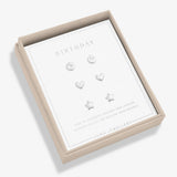 A boxed set of four silver stud earrings displayed on a white card inside a beige presentation box. The earrings include oval, heart, and star shapes, and the card reads 'BIRTHDAY' with 'JOMA JEWELLERY' at the bottom.
