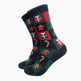 A pair of crew socks with a festive Christmas checkerboard pattern featuring red, dark green, black, white, and gingerbread men motifs, shown on a plain light gray background.