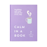 A lavender hardcover journal standing upright on a light marble surface against a warm off-white background. The cover features white text reading 'Soothing self-care rituals for every day', 'CALM IN A BOOK', a simple illustration of a mint green mug with white steam, and the brand name 'My Self-Love Supply' at the bottom right.