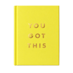 A hardcover notebook or journal in bright yellow with the phrase 'YOU GOT THIS' printed in metallic gold foil letters on the front cover, standing upright on a light marble-like surface against a soft light gray background.