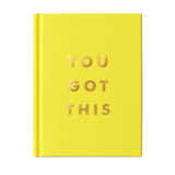 A hardcover notebook or journal in bright yellow with the phrase 'YOU GOT THIS' printed in metallic gold foil letters on the front cover, standing upright on a light marble-like surface against a soft light gray background.