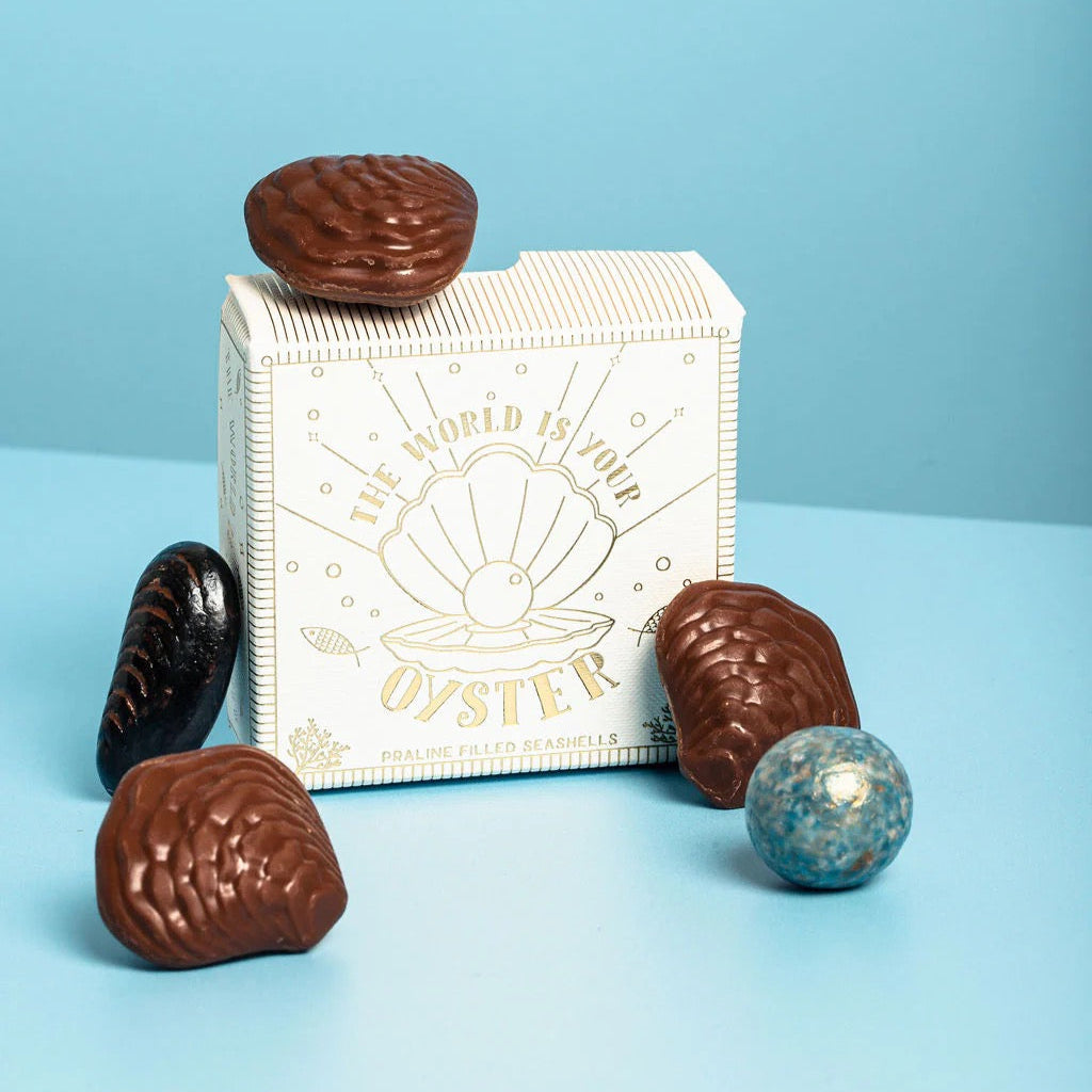 Chocolate oyster-shaped candies with a decorative box on a blue background