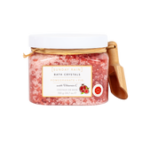 Sunday Rain Bath Crystals in a clear jar with a white lid, featuring pink pomegranate bath salts and a small wooden scoop on a white background.