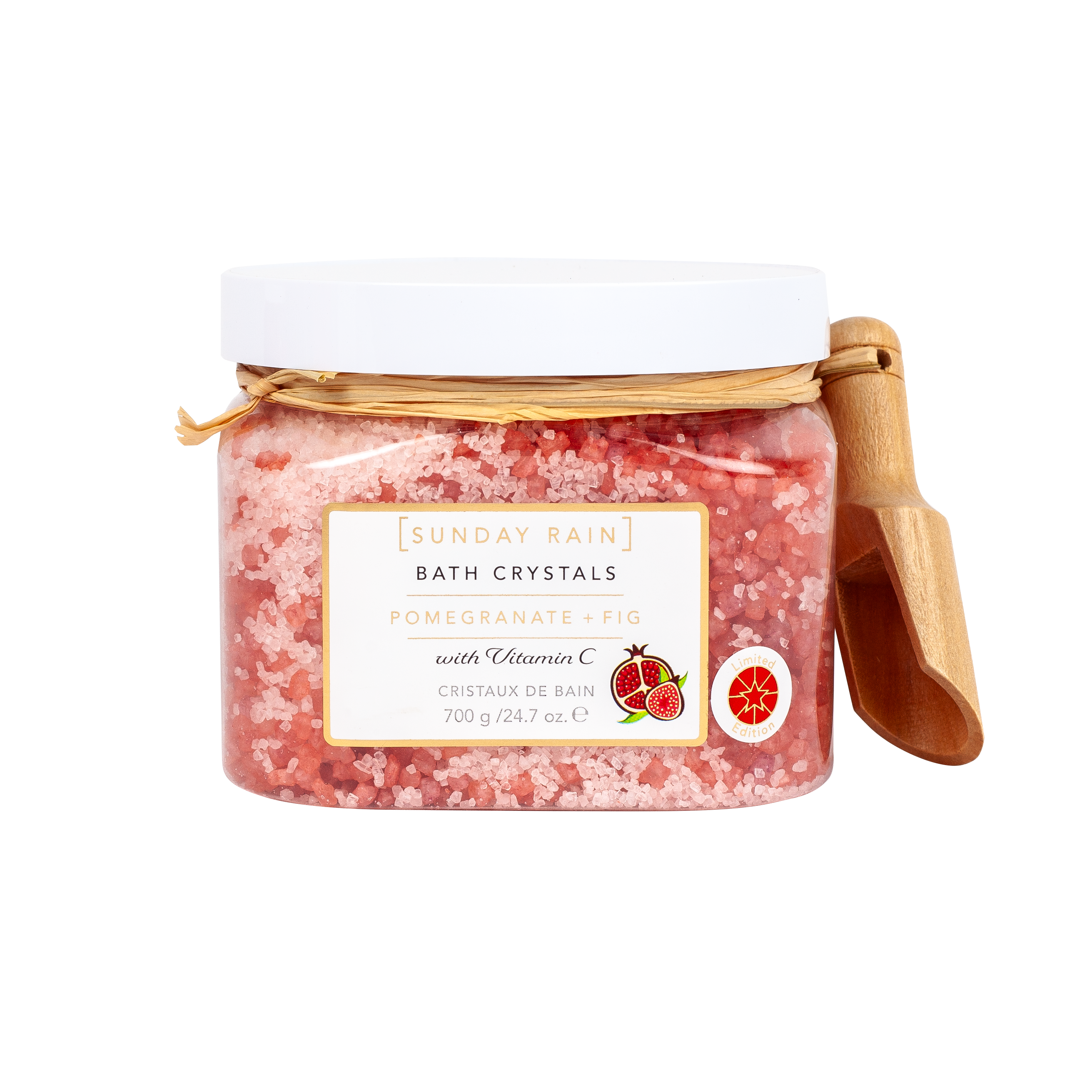 Sunday Rain Bath Crystals in a clear jar with a white lid, featuring pink pomegranate bath salts and a small wooden scoop on a white background.
