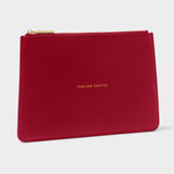 A red textured leather zip pouch with gold lettering that reads 'FEELING PERFECTIVE' and a gold zipper, shown on a light gray background.