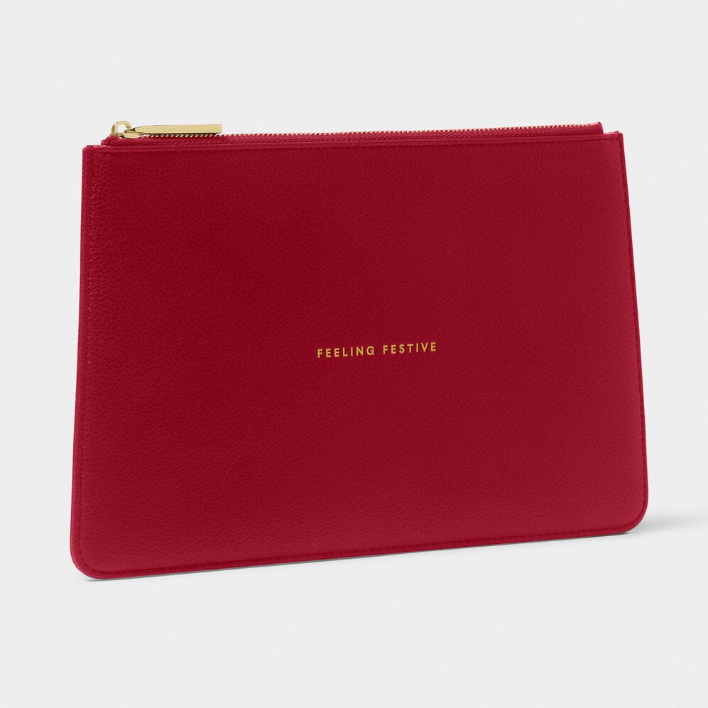 A red textured leather zip pouch with gold lettering that reads 'FEELING PERFECTIVE' and a gold zipper, shown on a light gray background.